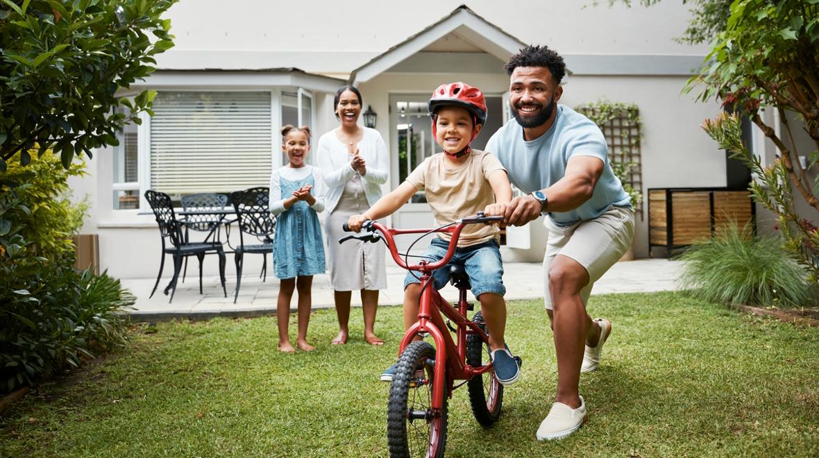 kid learning to ride a bike at home with their family