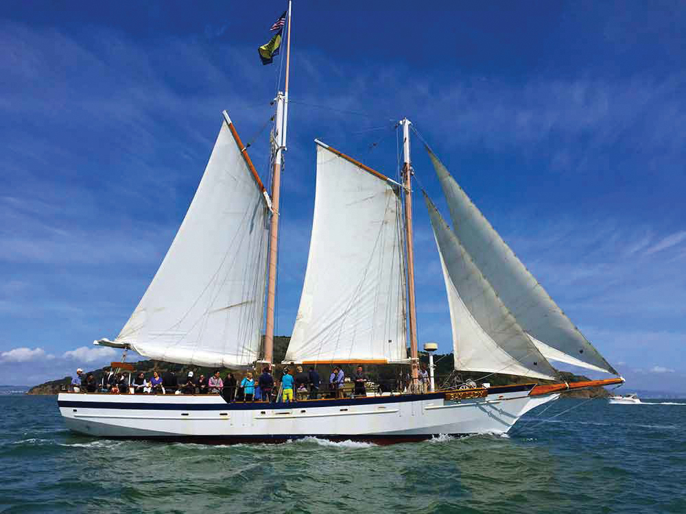 Seattle boat tours include Seattle's tall ship a sailboat with many passengers out on the Sound on a sunny day