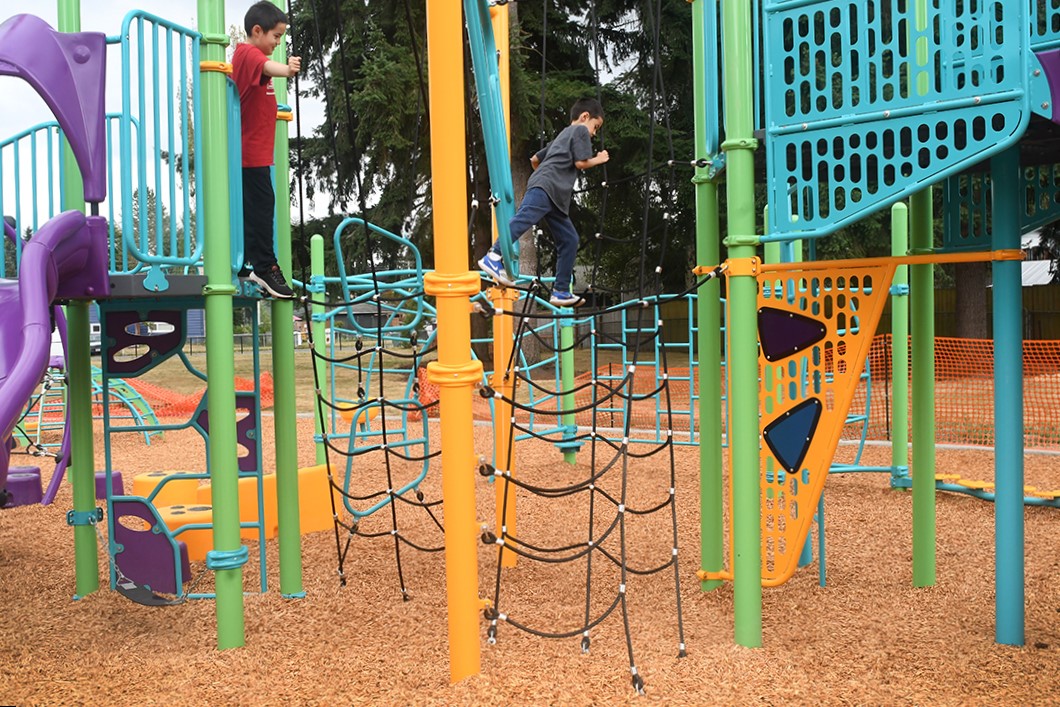 Kids play on the new playground equipment at Renton's new Cascade Park playground, a shaky rope bridge is a fun play element