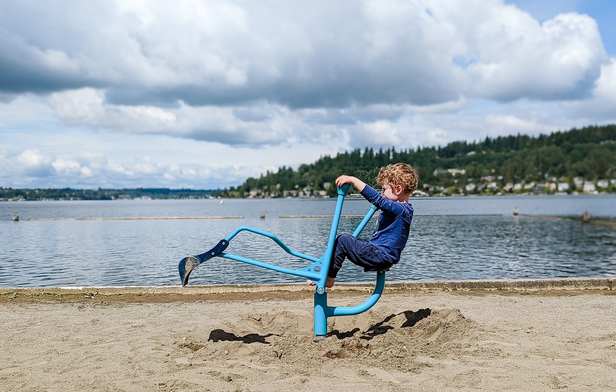 Young boy plays on a sand digger toy at Kennydale Beach Park in Renton with new playground equipment kids' activities swimming playground near Seattle