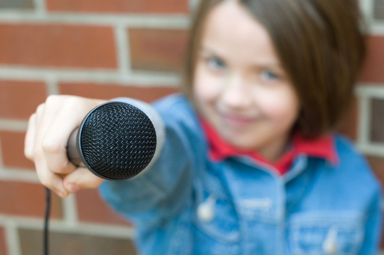 "Young girl holding up a microphone"