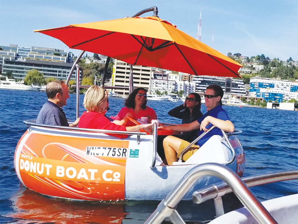 Adults on a Seattle boat cruise with Seattle Donut boats on Lake Union when it's sunny