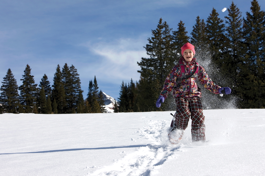 "Child wearing a snowsuit running in a field of snow"