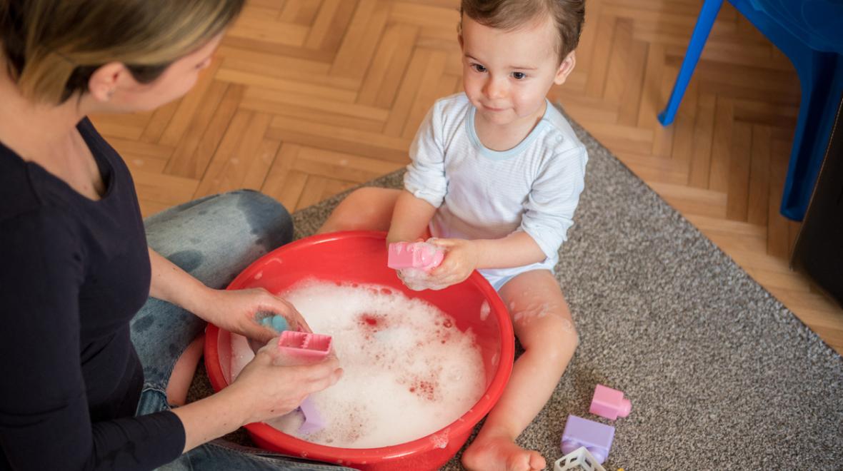 A mother and her toddler son make a game out of cleaning toys