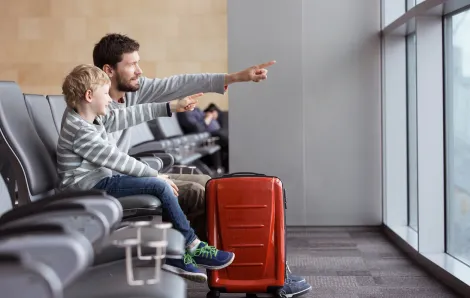little boy and father pointing out the window of an airport