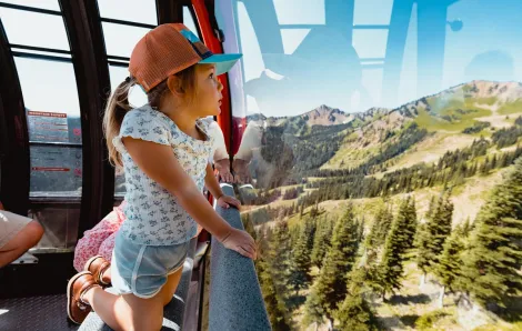 A young girl looks out from Crystal Mountain's Mt. Rainier Gondola among summer adventures for families at the ski area