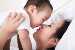 mother and baby enjoying motherhood holding up baby laying down smiling kissing