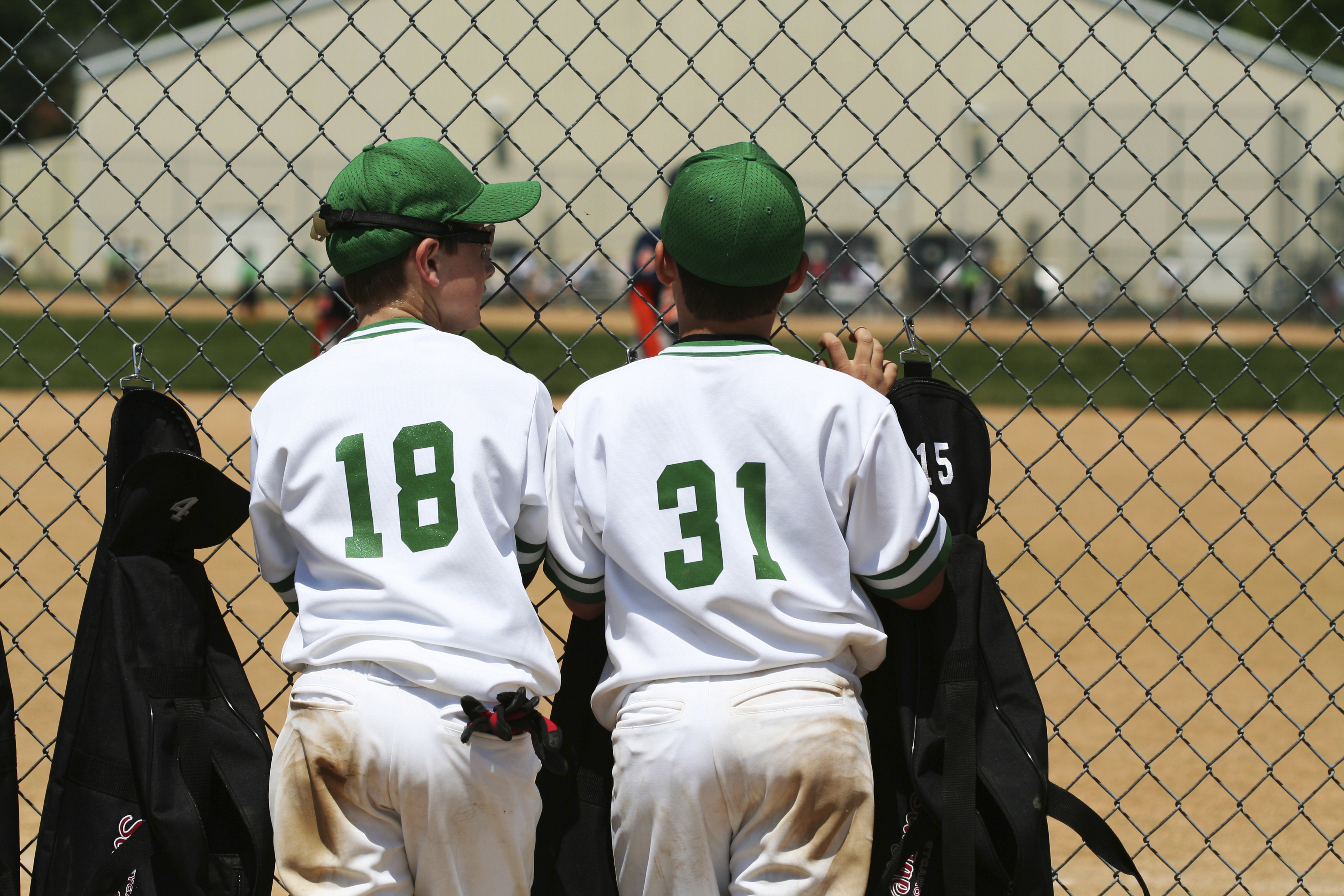 two boys in white and green baseball uniforms
