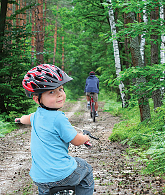 boy biking in the woods with his dad