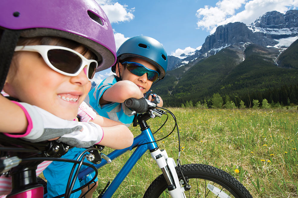 How to take your kids biking, kids in helmets on bikes in front of beautiful background