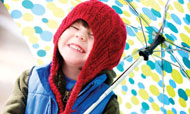 Boy wearing knit hat under umbrella