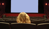Person facing blank screen in empty theatre.