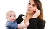 Woman in suit holding baby and talking on the phone