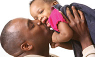 Father holding and kissing little girl