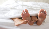 Feet intertwined under covers