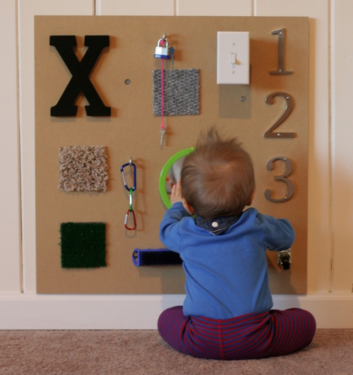 "Baby sitting in front of a sensory board"