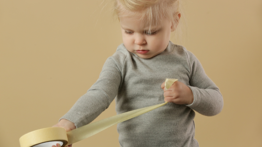 A toddler pulls on tape to set up a tape obstacle course for kids