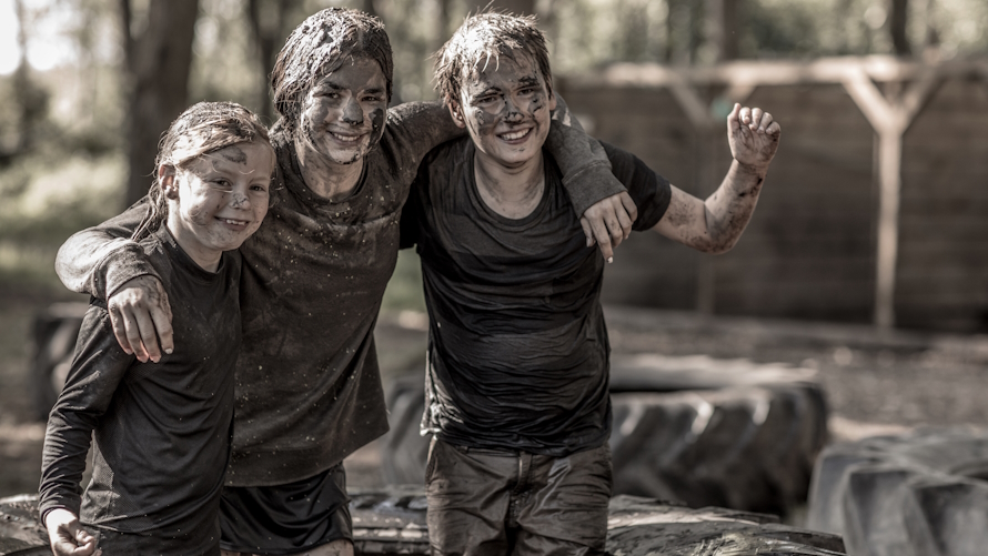 Three kids covered in mud after a mud obstacle course for kids
