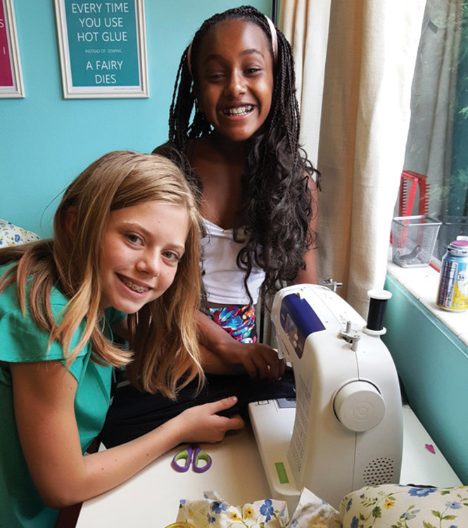 "Two girls at a sewing machine"