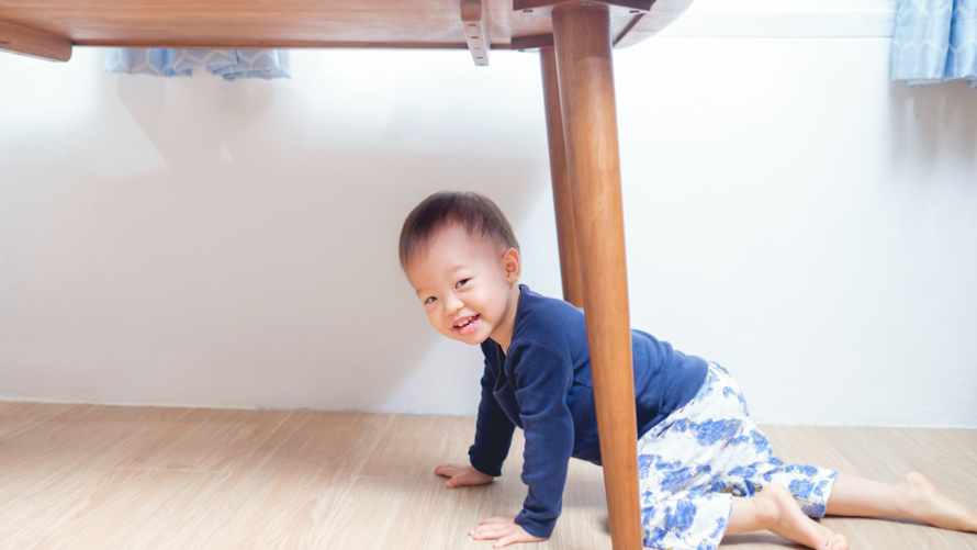 a toddler crawls under the table as part of an indoor obstacle course for kids