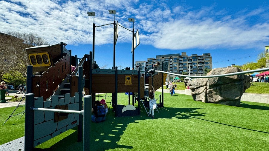 The Ballard Commons playground features a nautical theme with a large pirate ship, climbing rock, slide, and zip line.