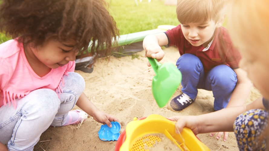 "Kids playing in a sandbox at an eco-friendly birthday party"