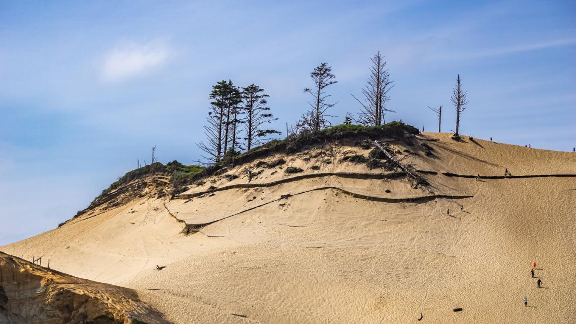 View of people climbing and descending the giant sand dune at Cape Kiwanda in Pacific City along the Oregon coast