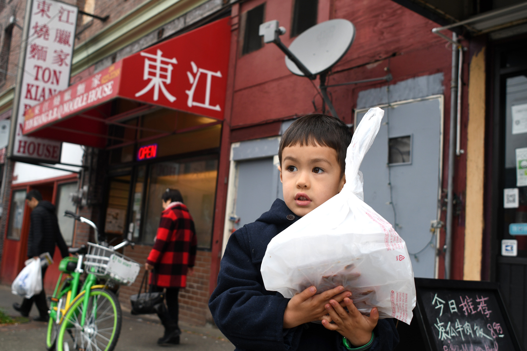 A boy holds a takeout bag from Ton Kiang Barbecue Noodle House among great places to eat for families in Seattle’s International District