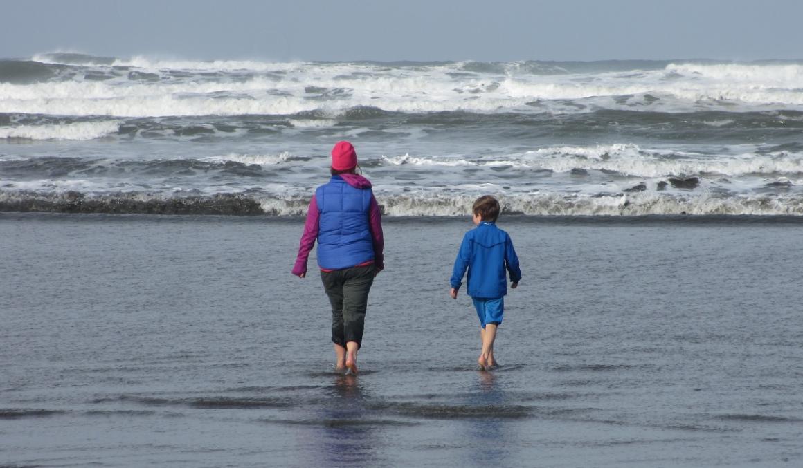 A mom and a 7 year old boy wade into the Pacific Ocean at Kalaloch in the off season and their toes get numb in seconds best storm watching destinations for seattle families