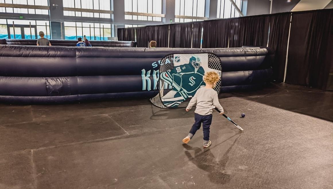Young boy playing floor hockey during a family fun zone game time at the grand opening of the new Kraken Community Iceplex