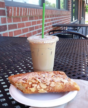 Slice of Larsen's Bakery Kringle and iced latte sitting on an outdoor table outside the bakery Ballard Seattle Washington