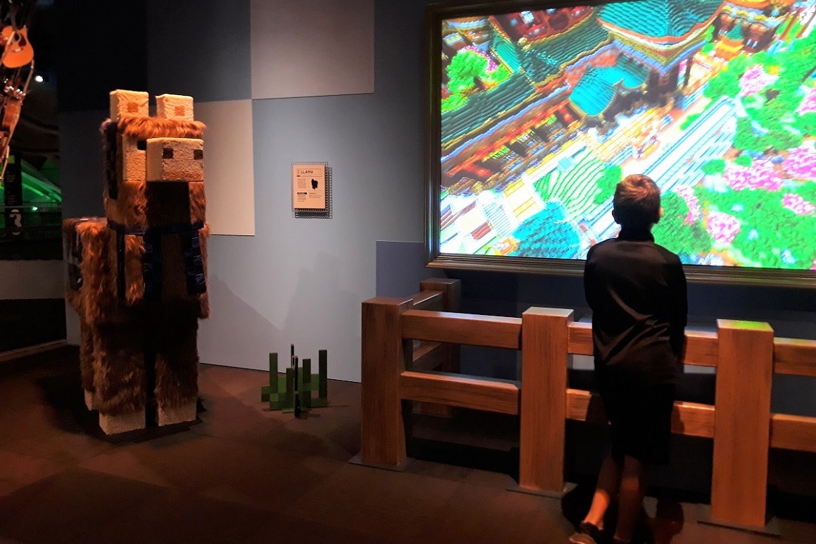 Minecraft-exhibit-llama-and-young-visitor-playing-large-screen-mopop-kids