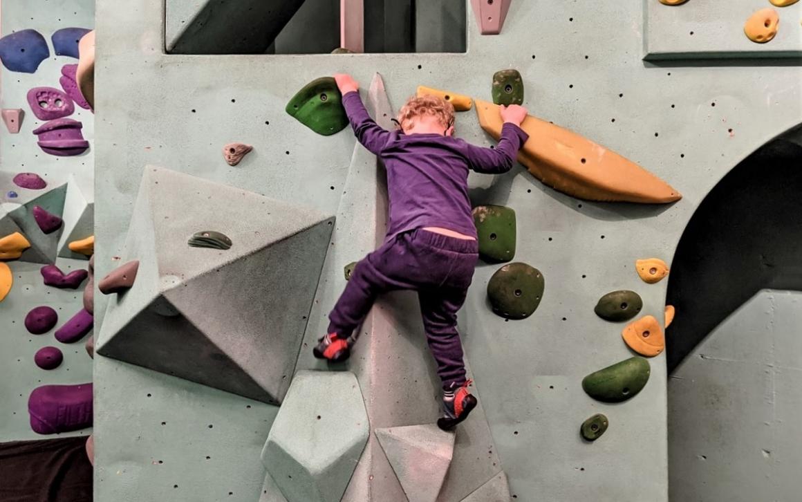 A young boy climbs at Seattle Bouldering Project among indoor play spaces for tots and kids during rainy days
