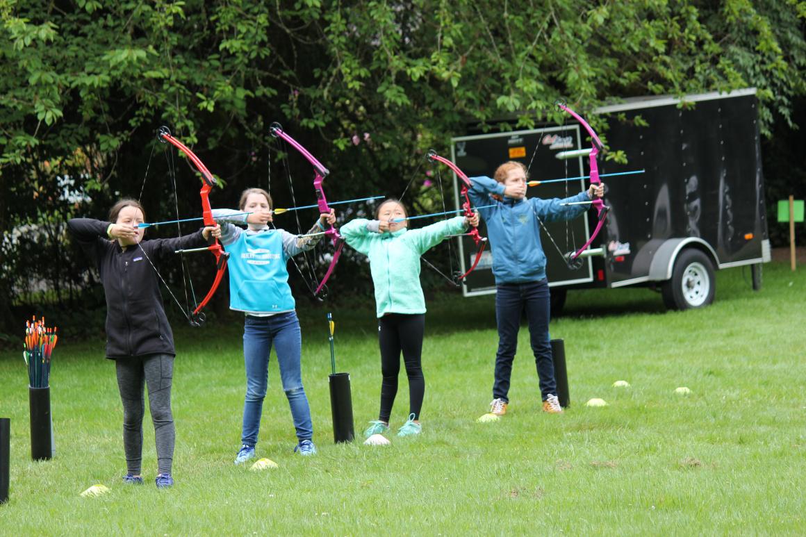A group of young girls practice archery