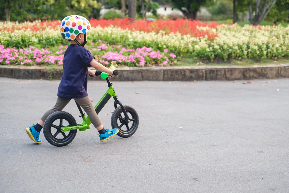 child-on-balance-bike-with-helmet-spring-tips-for-teaching-kid-to-ride-bike