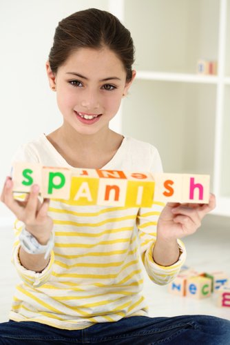 Young girl holding blocks that spell Spanish