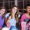 Three girls in pjs eating popcorn and watching a movie