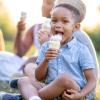 Boy sitting in the grass licking an ice cream cone from the best ice cream in Seattle