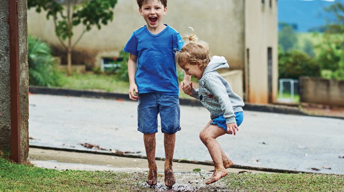 boys playing outside in a puddle