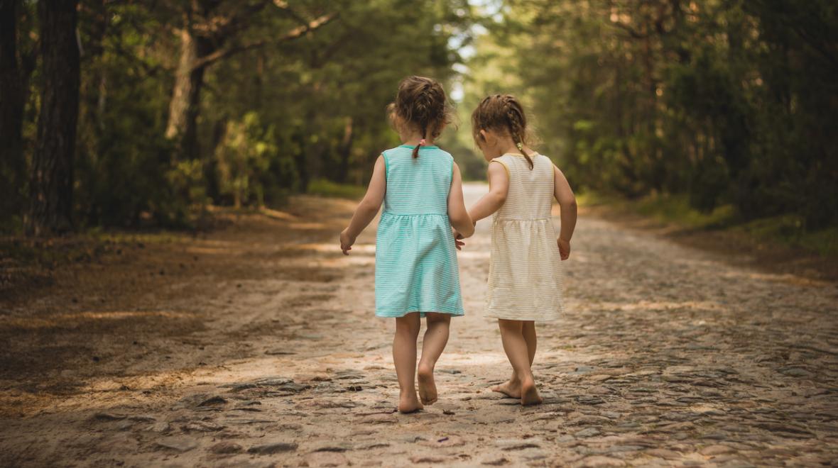 Twin girls walking down a dirt road