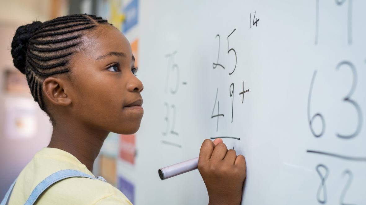 middle school girl doing math on a whiteboard