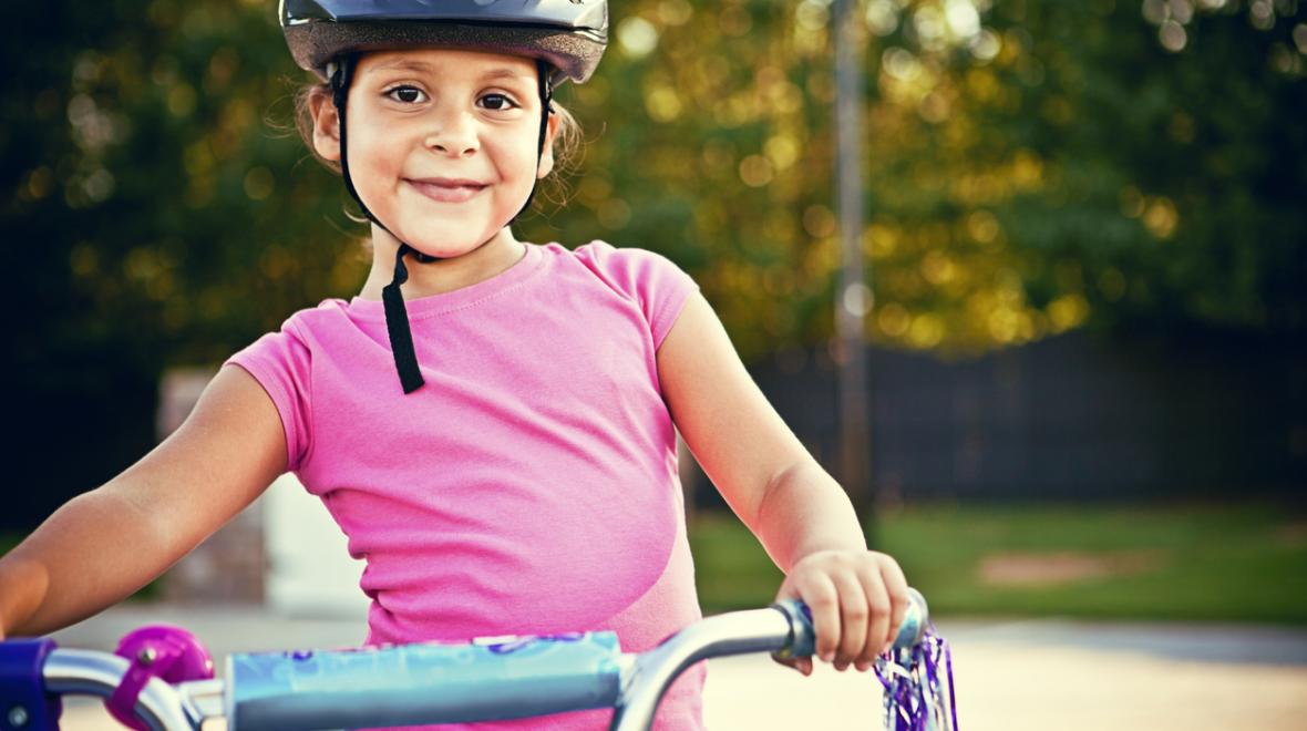 Girl wearing helmet holding bike handlebars bicycling families help cancel climate change