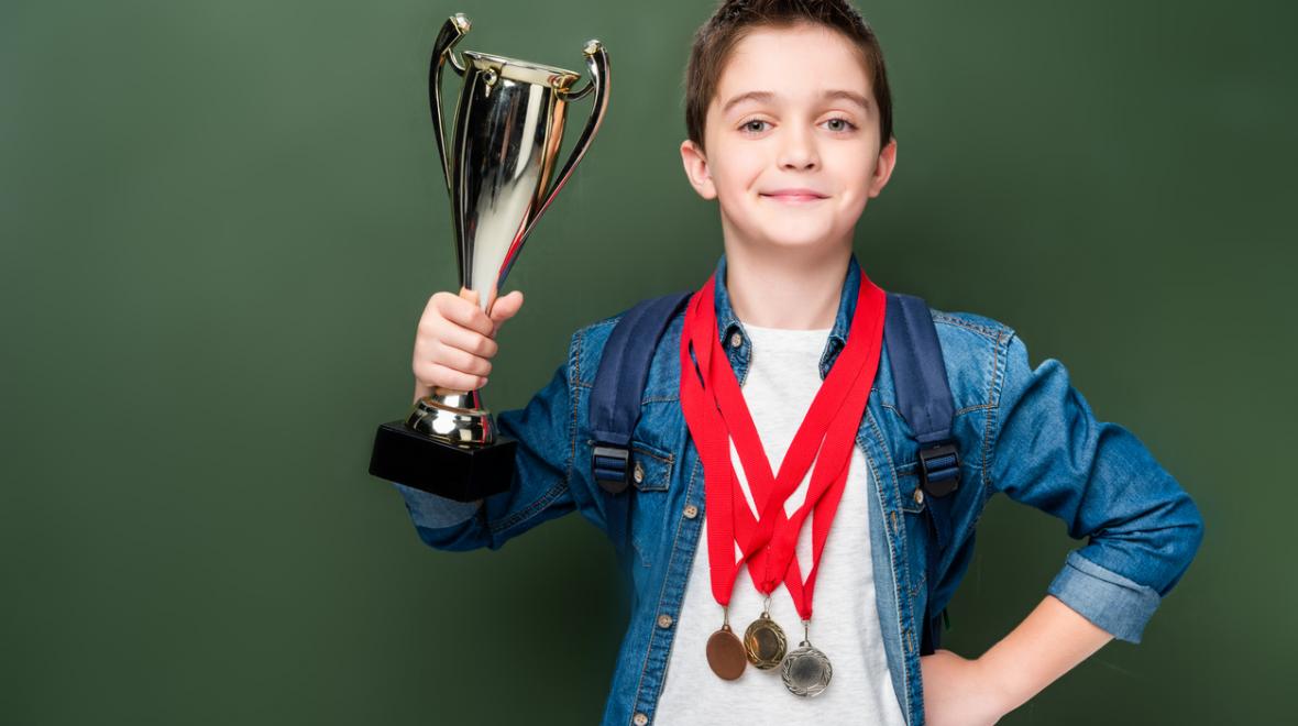 boy holding a trophy with gold medals around his neck