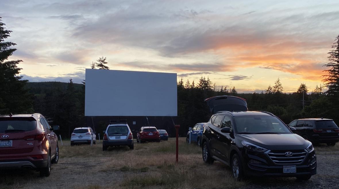 view of cars parked at a drive-in at sunset