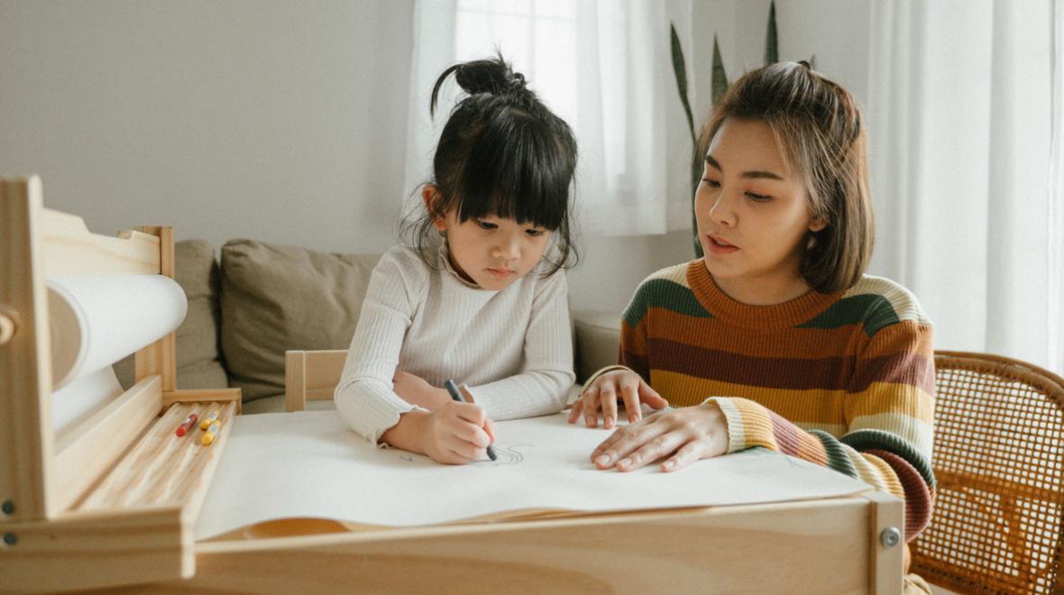 mother and daughter drawing at a child-size table together