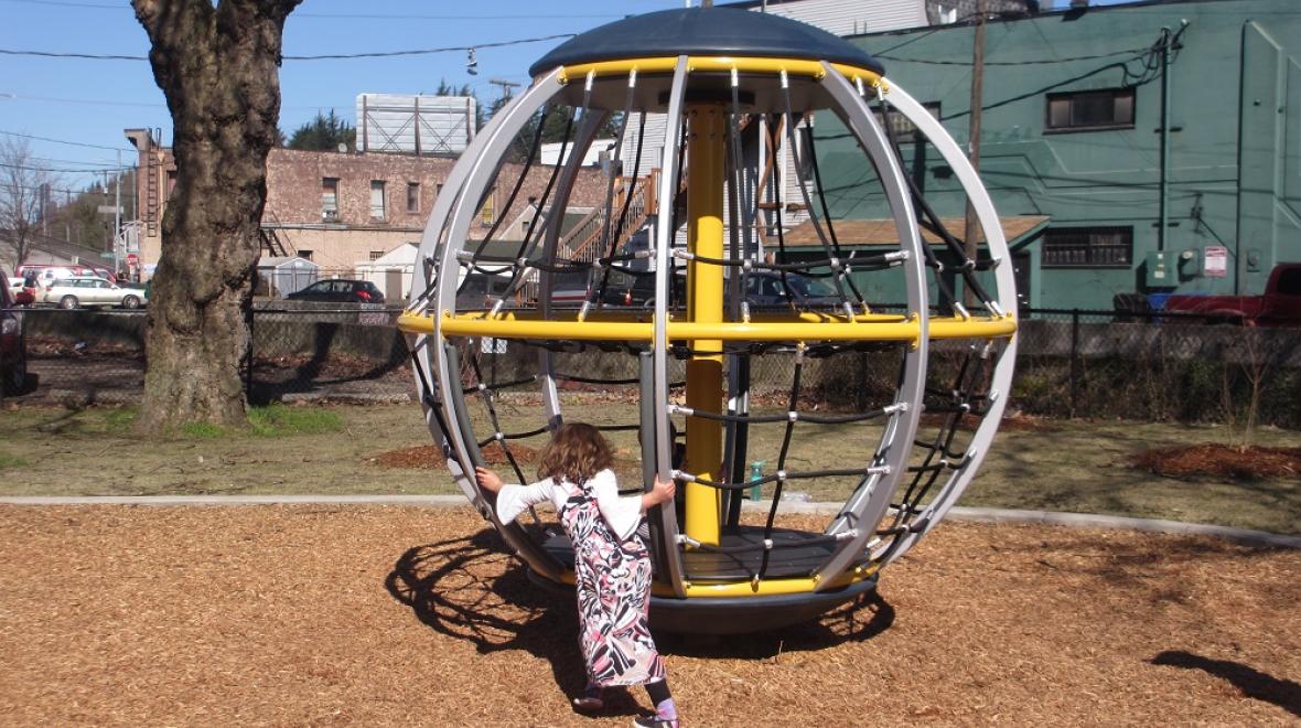 Girl on spinning merry-go-round climber at Georgetown Playfield Seattle playgrounds reopening October 6, 2020