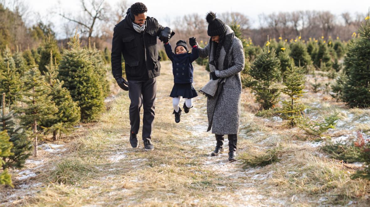 family of three walking through a christmas tree farm