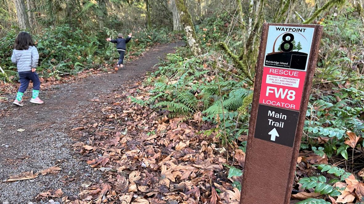 Kids on a hiking trail on Bainbridge Island passing a waypoint rescue finder sign