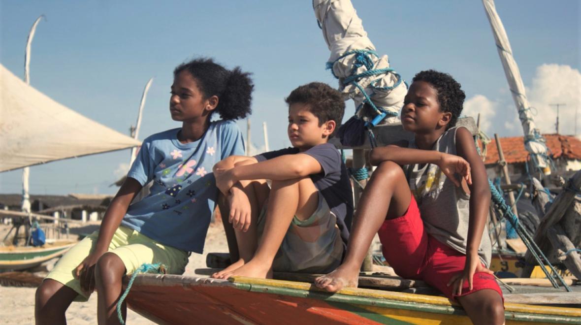 young warriors 1 childrens film festival still image of three kids sitting on the prow of a small boat on the beach