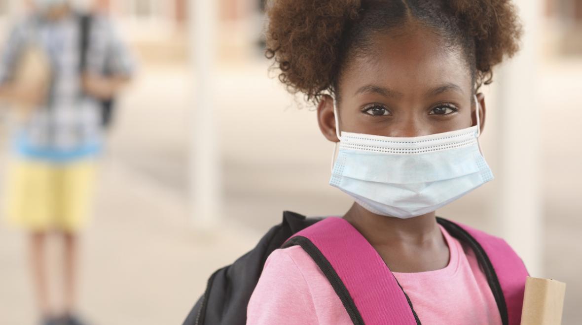 Young girl wearing a surgical mask and a school backpack